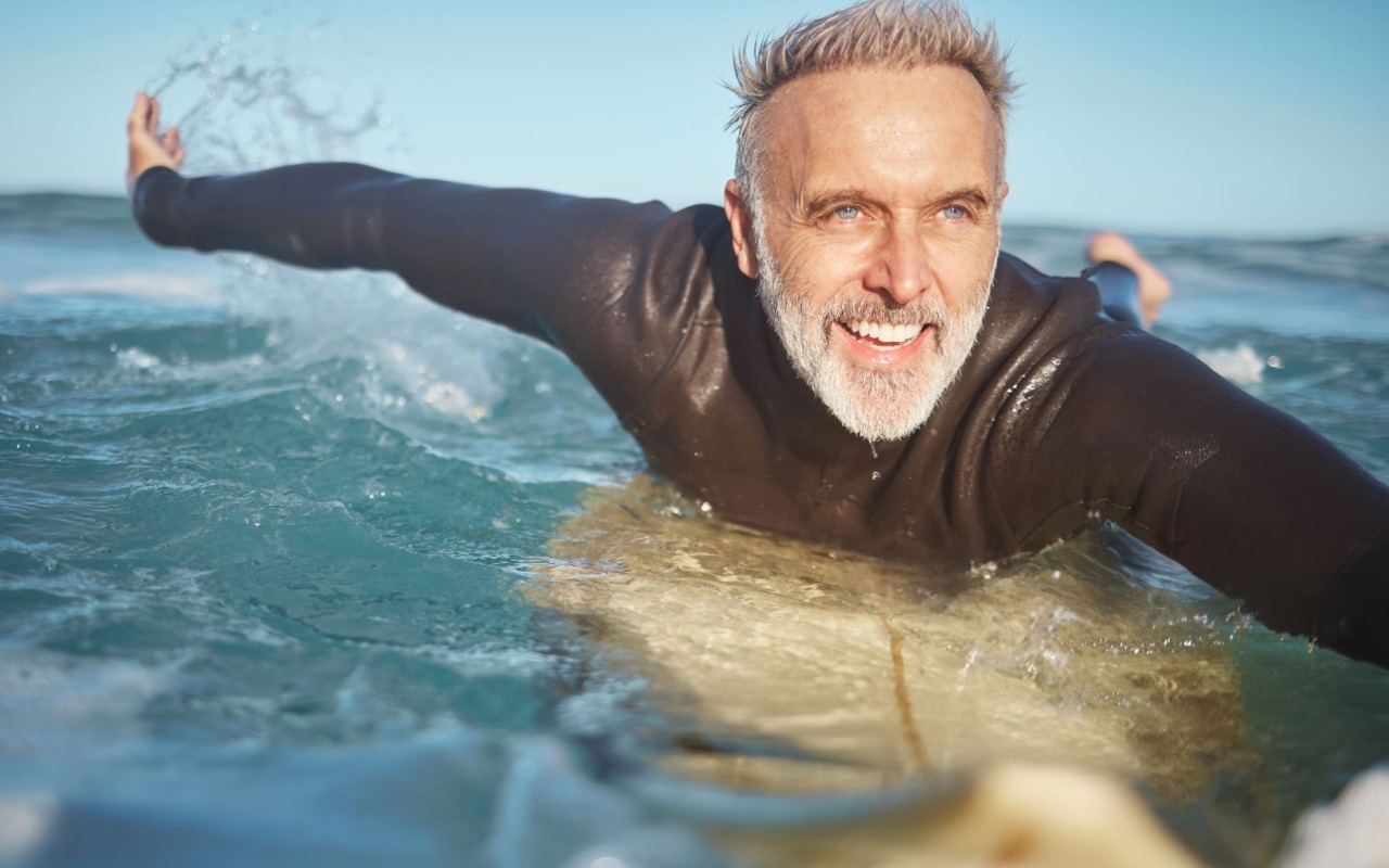 A man swims with smily face,wearing a black shirt.